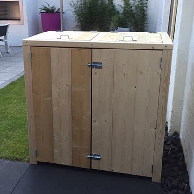 Onbehandelde houten kliko-ombouw met twee deuren in een tuin
