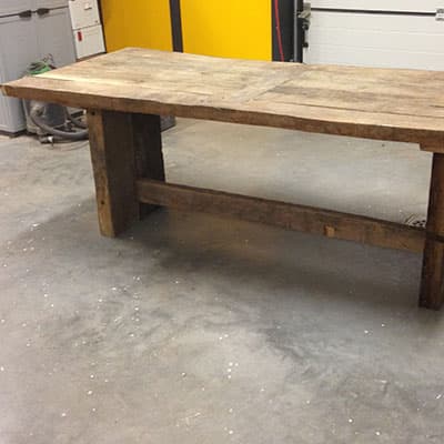 Afgewerkte eikenhouten tafel met bijpassende bank in een werkplaats